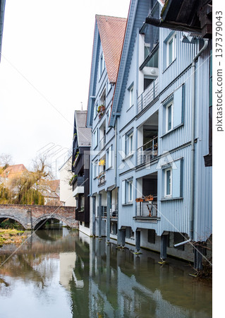 A tranquil canal in the fishermans quarter of Ulm, Germany. Reflections of colorful buildings line the water edge, creating a serene urban scene. A tranquil canal in the fishermans quarter of Ulm, Germany. Reflections of colorful buildings line the water edge, creating a serene urban scene. 137379043