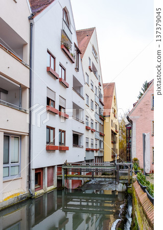 A tranquil canal in the fishermans quarter of Ulm, Germany. Reflections of colorful buildings line the water edge, creating a serene urban scene. A tranquil canal in the fishermans quarter of Ulm, Germany. Reflections of colorful buildings line the water edge, creating a serene urban scene. 137379045