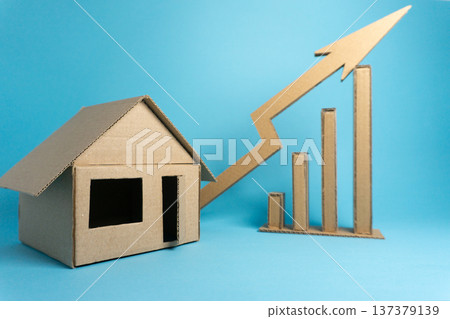 Cardboard house model with growth chart on blue background showing real estate market trends and financial concepts Cardboard house model with growth chart on blue background showing real estate market trends and financial concepts 137379139