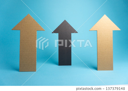 Three cardboard arrows point upward on a blue background during daylight Three cardboard arrows point upward on a blue background during daylight 137379148