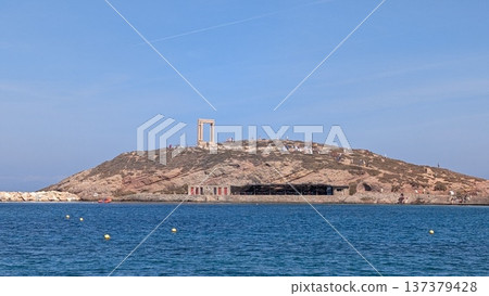 View of a small island with an ancient ruins gate on a hill between the sea and blue sky View of a small island with an ancient ruins gate on a hill between the sea and blue sky 137379428