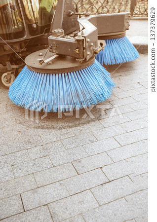 Pair of blue mechanical brushes of a cleaning truck on a sunny sidewalk Pair of blue mechanical brushes of a cleaning truck on a sunny sidewalk 137379629