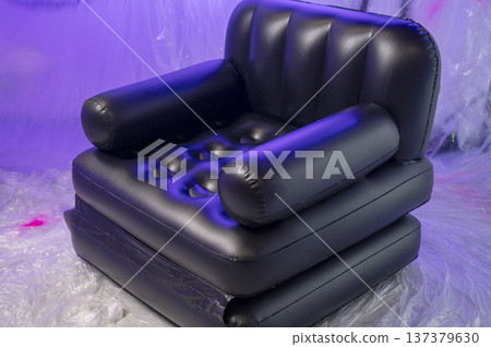 Inflatable armchair illuminated by vibrant colorful studio lights in a dark room. Inflatable armchair illuminated by vibrant colorful studio lights in a dark room. 137379630