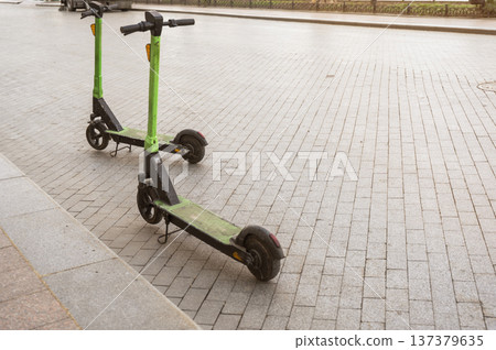 Two electric scooters parked on a city sidewalk for rental service Two electric scooters parked on a city sidewalk for rental service 137379635