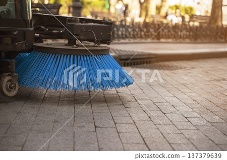 Blue synthetic bristles of a road cleaning machine part on a granite sidewalk. Blue synthetic bristles of a road cleaning machine part on a granite sidewalk. 137379639
