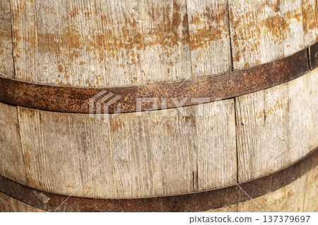 Close up of an old wooden wine barrel with rusty metal hoops and weathered texture. Close up of an old wooden wine barrel with rusty metal hoops and weathered texture. 137379697