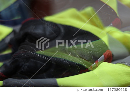 A leather bicycle glove on a reflective vest. 137380618