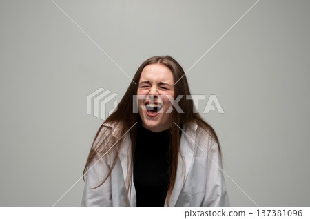 Young woman screaming loudly, expressing intense anger, stress, frustration, and emotional breakdown on gray background Young woman screaming loudly, expressing intense anger, stress, frustration, and emotional breakdown on gray background 137381096