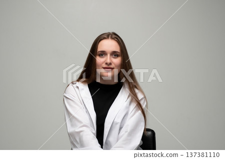 Young woman with long brown hair wearing a white shirt in a studio, looking at camera confidently Young woman with long brown hair wearing a white shirt in a studio, looking at camera confidently 137381110