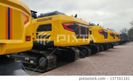 Row of modern yellow excavators parked on pavement. Heavy industrial construction machinery fleet rear view Row of modern yellow excavators parked on pavement. Heavy industrial construction machinery fleet rear view 137381181