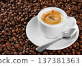 Small white espresso cup with splash and drop, brimming with aromatic coffee resting on bed of roasted beans 137381363