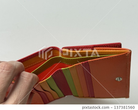 Colorful empty wallet open showing multiple card slots, held by hand 137381560