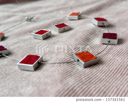Colorful geometric jewelry necklace with square pendant design on textured fabric background Colorful geometric jewelry necklace with square pendant design on textured fabric background 137381561