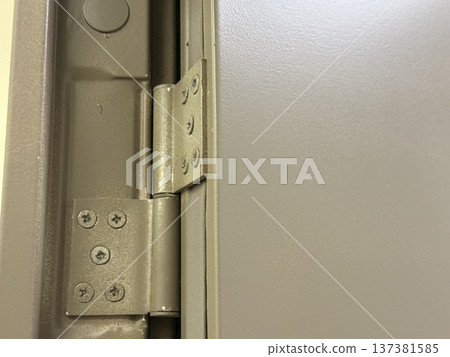 Metal door hinge close-up showcases screws and mechanism, ideal for industrial or construction themes 137381585