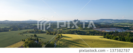 View of the countryside in Bohemian Paradise with Trosky Castle in the distance. This summer landscape shows green fields and hills under a clear sky in Czechia. 137382787