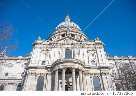 St Pauls Cathedral is shown from below against a clear blue sky in London. The structure features a large dome and detailed architecture. Visitors can enjoy the view during the day. 137382800