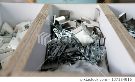 Metal hardware and furniture fittings sorted in a wooden organizer box in a workshop. 137384916