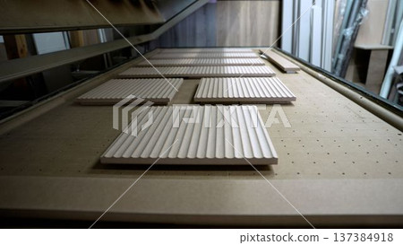 CNC machine milling fluted wood panels. Furniture production and modern woodworking in a carpentry workshop. CNC machine milling fluted wood panels. Furniture production and modern woodworking in a carpentry workshop. 137384918