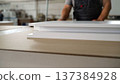 Close-up of white furniture panels on a workbench with a craftsman in a workshop 137384928