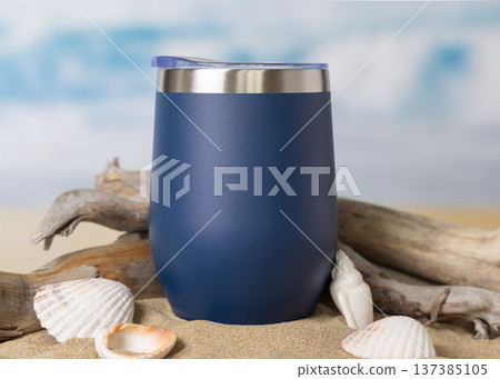 Wine tumbler mockup with blank white 12oz stainless steel cup on sand with seashells and driftwood 137385105