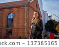 Woman eating pastry on city street near brick building 137385165