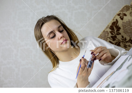 Fragile girl tries to open can of paint for painting. The tightly sealed paint box is beyond young woman strength. The girl struggles to open the tightly sealed jars. The problem of weak girl Fragile girl tries to open can of paint for painting. The tightly sealed paint box is beyond young woman strength. The girl struggles to open the tightly sealed jars. The problem of weak girl 137386119