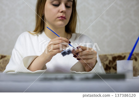 Special brush in hands of professional artist. Girl applies paint to the bristles of painting brush. Expensive hobby equipment. High quality artist tools with brush and paints Special brush in hands of professional artist. Girl applies paint to the bristles of painting brush. Expensive hobby equipment. High quality artist tools with brush and paints 137386120