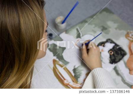 View from behind girl with blurred background depicting painting being created by young artist. Loneliness at early age motivates girl to paint. Hobby of painting picture alone, no family and friends View from behind girl with blurred background depicting painting being created by young artist. Loneliness at early age motivates girl to paint. Hobby of painting picture alone, no family and friends 137386146