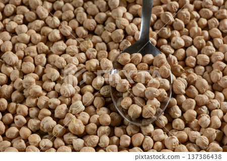 Raw uncooked chickpeas in a spoon close-up. Raw uncooked chickpeas in a spoon close-up. 137386438
