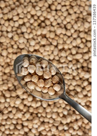 Raw uncooked chickpeas in a spoon close-up. Raw uncooked chickpeas in a spoon close-up. 137386439
