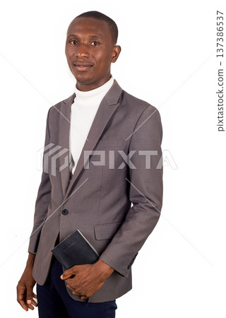 young man standing in jacket and holding a Bible. young man standing in jacket and holding a Bible. 137386537