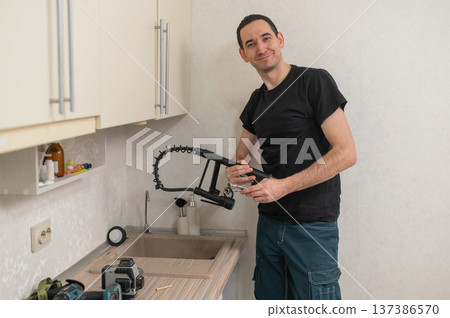 A plumber is replacing a faucet in the kitchen. A plumber is replacing a faucet in the kitchen. 137386570