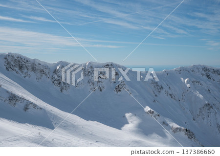 Snow covered mountain ridge of Krasnaya Polyana under clear blue sky with expansive alpine winter landscape in Sochi region. Travel marketing, winter tourism promotion, alpine adventure 137386660