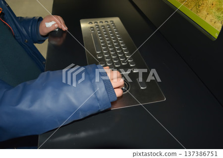 A close-up of a child's hands using an adaptive computer keyboard with large keys and a trackball. Concept: rehabilitation tools and educational support for children with disabilities. A close-up of a child's hands using an adaptive computer keyboard with large keys and a trackball. Concept: rehabilitation tools and educational support for children with disabilities. 137386751