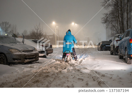 Transportation collapse in city during snowstorm, delivery person on bike walking through snow. Transportation collapse in city during snowstorm, delivery person on bike walking through snow. 137387194