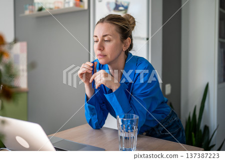 Concentrated on screen laptop woman freelancer pondering project idea holding pen working from home Concentrated on screen laptop woman freelancer pondering project idea holding pen working from home 137387223