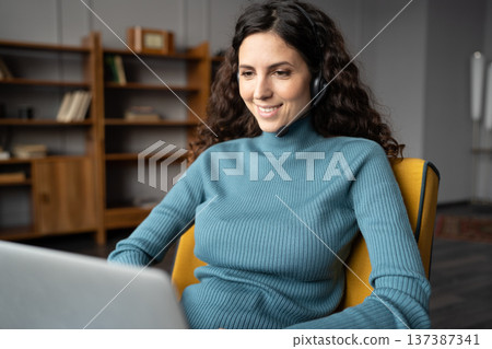 Smiling self-employed women freelancer in wireless headset with mic giving online consultation Smiling self-employed women freelancer in wireless headset with mic giving online consultation 137387341