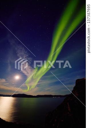 Aurora borealis over ocean in Teriberka, Russia, Murmansk region, Northern lights, Starry sky with polar lights and clouds. Night autumn landscape with bright aurora, stars, sea Aurora borealis over ocean in Teriberka, Russia, Murmansk region, Northern lights, Starry sky with polar lights and clouds. Night autumn landscape with bright aurora, stars, sea 137387695