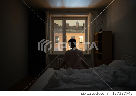 Thoughtful senior woman with insomnia sits in bed in dark bedroom, sleep problems caused by stress. 137387743