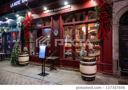 Lyon, france. December 27,2023. La mere maquerelle bouchon in lyon at night, festive illuminated facade with wine barrels and warm holiday decorations 137387898
