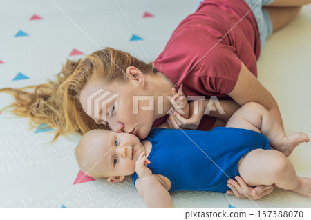 Mother and baby lying on a soft play mat at home, playing, talking and sharing a joyful moment together. Authentic family lifestyle, early childhood development and emotional bonding. Parenting and 137388070