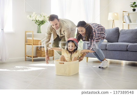 Happy family playing airplane flight, parents pushing daughter sitting inside box 137389548