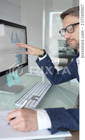 Professional businessman in a blue jacket working on desktop computer in modern office, focusing on his work and business tasks. Business people concept Professional businessman in a blue jacket working on desktop computer in modern office, focusing on his work and business tasks. Business people concept 137389987