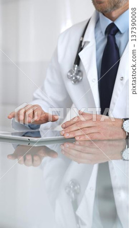 Doctor using digital tablet, consulting with patient, working in healthcare office, telemedicine and medical technology concept. Medicine and health care Doctor using digital tablet, consulting with patient, working in healthcare office, telemedicine and medical technology concept. Medicine and health care 137390008