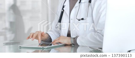 Doctor using digital tablet for remote medical consultation, providing modern healthcare services, telehealth concept. Medicine and health care Doctor using digital tablet for remote medical consultation, providing modern healthcare services, telehealth concept. Medicine and health care 137390113