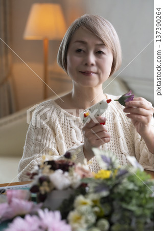 老婦人在客廳製作插花作品 老婦人在客廳製作插花作品 137390264