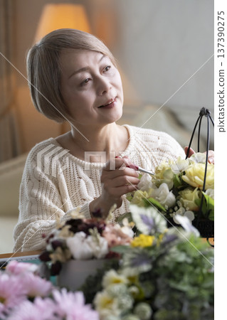 Senior woman making a flower arrangement as a hobby in the living room Senior woman making a flower arrangement as a hobby in the living room 137390275