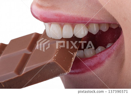 Close up of female mouth biting chocolate highlighting aesthetic ceramic veneers and perfect smile Close up of female mouth biting chocolate highlighting aesthetic ceramic veneers and perfect smile 137390371