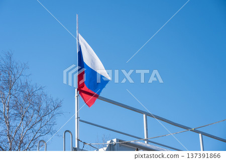 A Russian federation flag against blue sky. The Russian Federation state flag is rectangular in form and comprises three equal horizontal stripes. 137391866