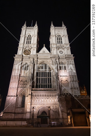 Westminster Abbey, London. The Gothic architecture is beautifully illuminated under the evening sky, showcasing the detailed facade and majestic towers. Westminster Abbey, London. The Gothic architecture is beautifully illuminated under the evening sky, showcasing the detailed facade and majestic towers. 137392169